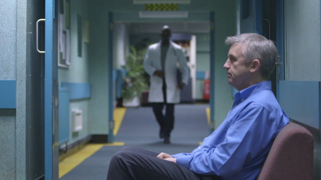 Worried man sitting alone in a hospital waiting area waits for news 