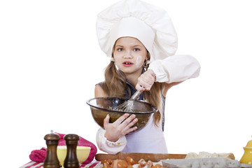 Little girl cook whips whisk eggs in a large plate