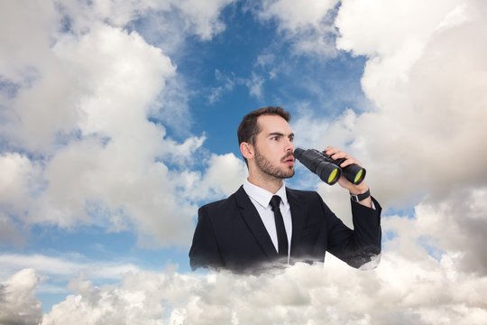 Surprised businessman standing and holding binoculars