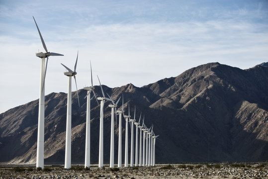 Wind power turbines in the landscape. A large number of turbine powers on a plain against a mountain backdrop. 
