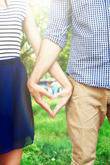 Loving couple holding hands in shape of heart, close-up