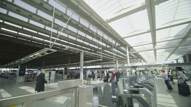 Travelers & commuters passing through ticket barrier at a London railway station