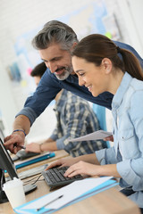 Trainer with student working on desktop computer