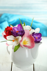 Beautiful spring flowers on wooden table on blue background
