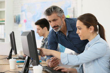 Trainer with student working on desktop computer