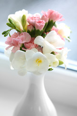 Beautiful spring flowers in vase on windowsill background