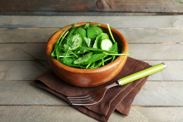Green salad in bowl on wooden background