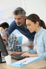 Trainer with student working on desktop computer © goodluz