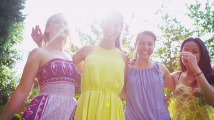 Portrait of cheerful female friends with sunlight streaming through the trees