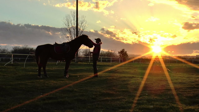 Girl cuddles a horse in sunset.