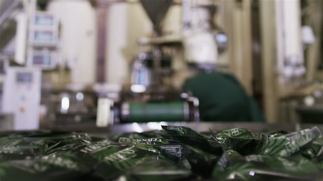 Packets of fresh coffee moving along factory conveyor belt ready for packing