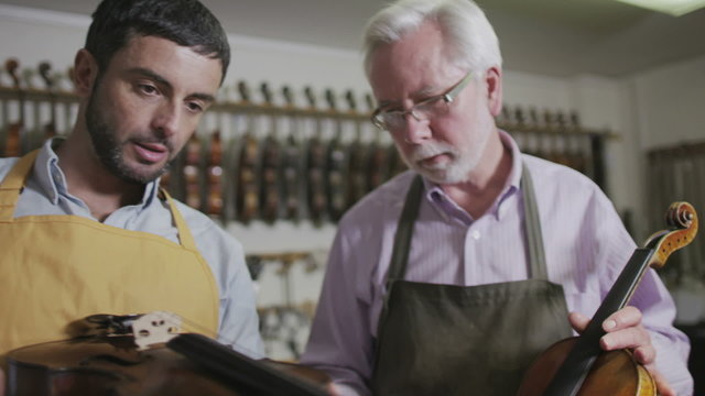 Father and son shopping together, looking at violins in a musical store