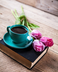 Cup of coffee on book with flowers.