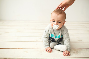 Naklejka premium One year old cute baby boy sitting on wooden floor