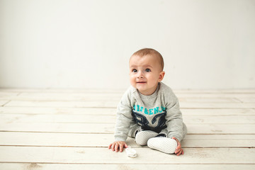 Naklejka premium One year old cute baby boy sitting on wooden floor