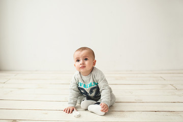 One year old cute baby boy sitting on wooden floor