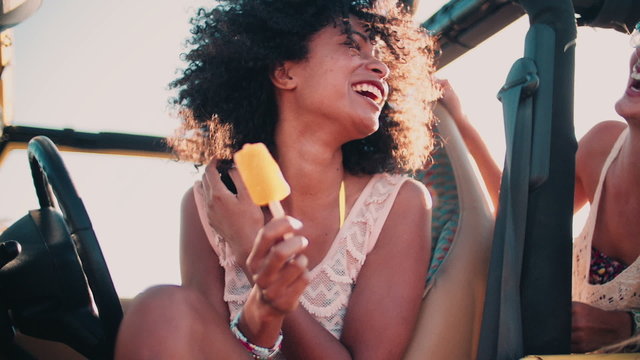 Afro girl at the beach with friend eating ice cream