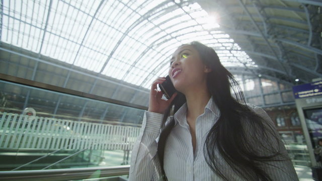 Beautiful woman on the phone as she walks through iconic London train station