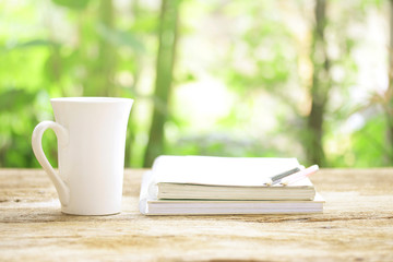 Notebook  and  white cup on wooden table