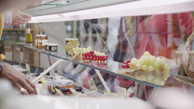 Staff and customers at the cheese counter of a small local delicatessen. No face