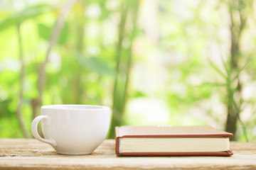 Notebook  and  white cup on wooden table