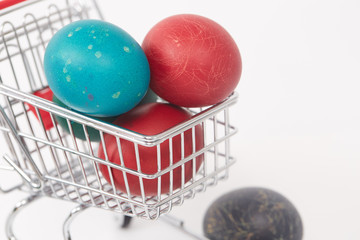 Easter colorful painted eggs in the shopping cart and near the t