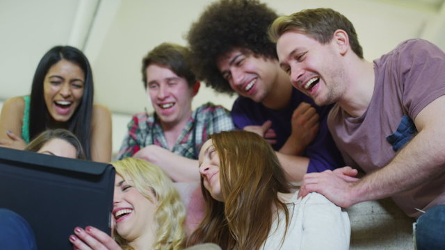 Happy casual group of young friends relaxing with a tablet computer