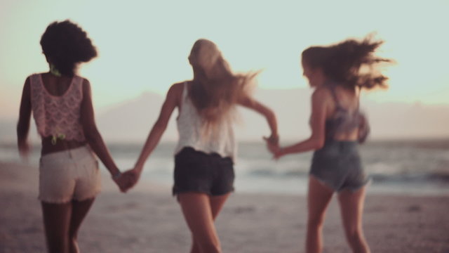 Girls running and holding hands on a sunset beach