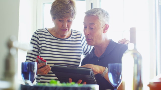 Couple relaxing together at home with a computer tablet.