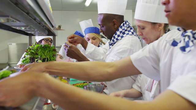 Mixed ethnicity team of professional chefs preparing food ready for service
