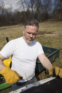 Man wearing work gloves taking shingles off roof