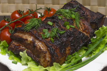 Pork ribs on the salad leaves with cherry tomatoes