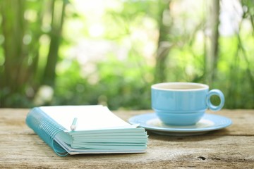 coffee in blue cup and notebook on wooden table