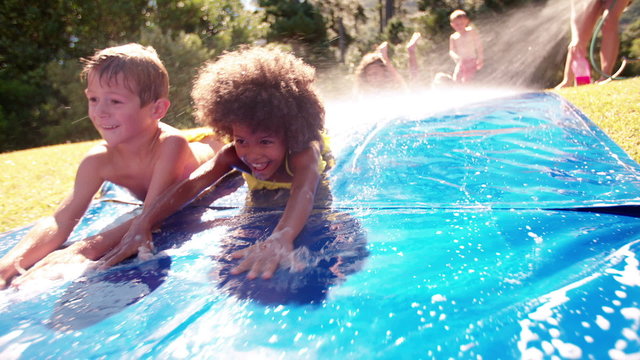 Afro girl and friends playing on a water slide