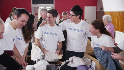 Charity volunteers in printed t. shirts sort through donated food and clothing