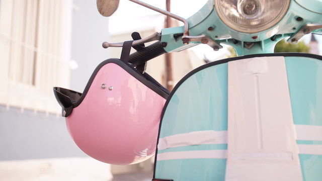 Pink helmet hanging on blue scooter