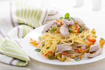 Pasta or spaghetti with chicken and herbs on a white plate