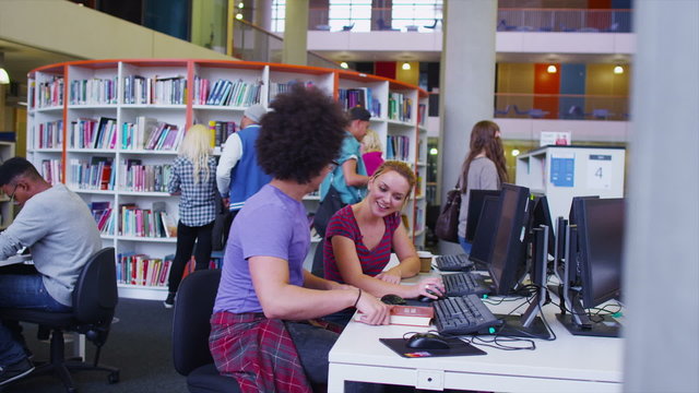 Diverse student group working and studying together in college library.