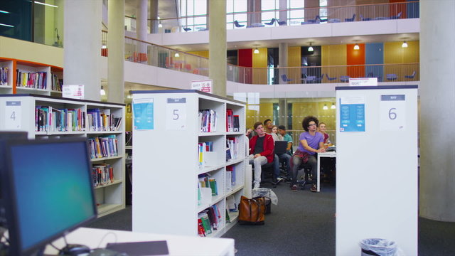 Student group listening to the teacher and working in a room full of computers