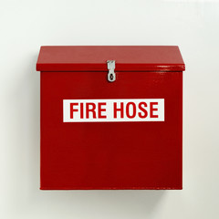 Fire hose box in bright red hung on white wall