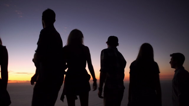 Teens looking at the ocean after sunset on a mountain