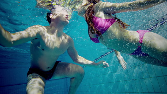 Attractive and playful couple kissing underwater.
