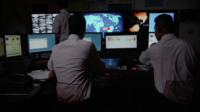 Security personnel watching the screens in a dark system control room