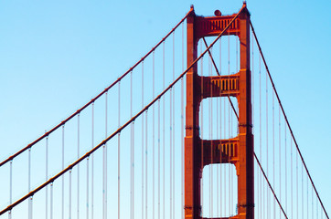 Golden Gate Bridge and suspension cables on light blue sky