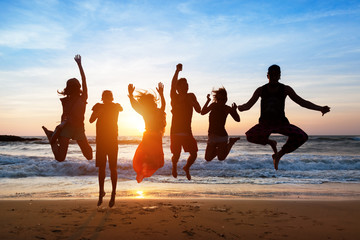 Six people jumping on beach at sunset. - Powered by Adobe