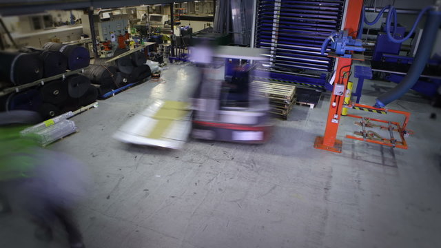 Time lapse clip of busy warehouse workers lifting and moving empty pallets