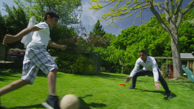 Cute young boy playing sports with his father, in the garden on a summer day
