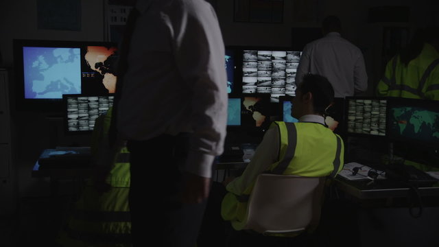 Security personnel watching the screens in a dark system control room