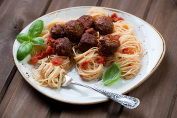 Spaghetti and meatballs over dark wooden surface, close-up