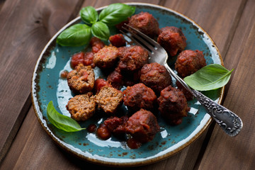 Meatballs with tomato sauce on a turquoise plate, studio shot